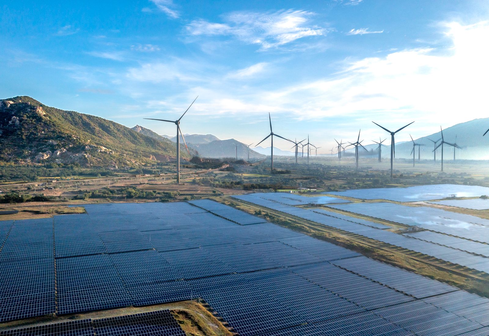 Solar array with wind turbines behind it